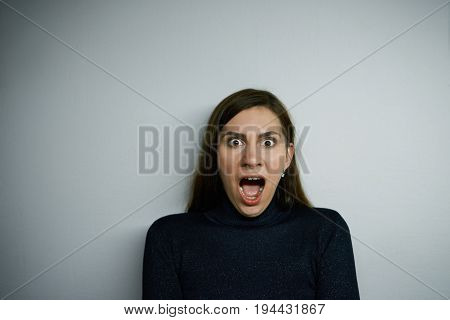 Shocked hysterical young Caucasian woman in black turtleneck sweater shouting staring at camera with despair and terror feeling panic while being late for plane exam or some important event