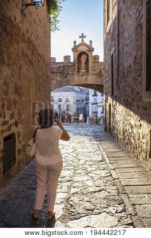 Tourist taking pictures close to Star Arch or Arco de la Estrella Caceres. Sunset light