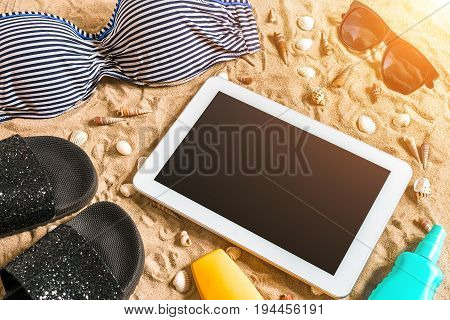 Summer bikini and accessories stylish beach set, Beach bikini summer outfit and sea sand as background, Top View, Concept. Copy space. Sun flare