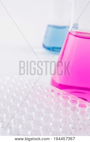 research, science and clinic background. 96 well micro plate and  laboratory beakers with colorful liquids and reagents.