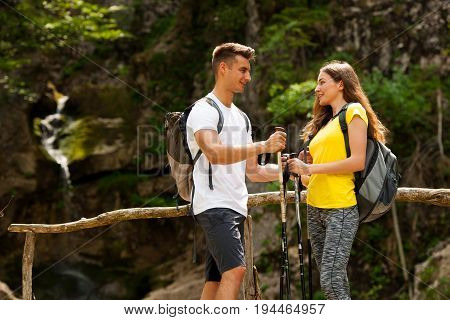 Active Young Cople Hiking On A Wooden Brifge Over Mountain Creek