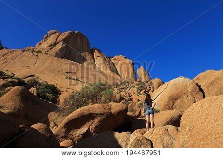 Girl at Spitzkoppe aka Sptizkop - unique rock formation in Damaraland landscape Namibia Africa.