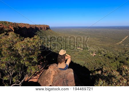 Girl Sitting On Stone On The Cliff At An African Landscape. Waterberg Plateau, Namibia