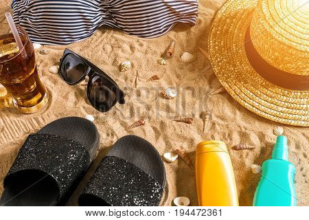 Summer bikini and accessories stylish beach set, Beach bikini summer outfit and sea sand as background, Top View, Concept. Copy space. Sun flare