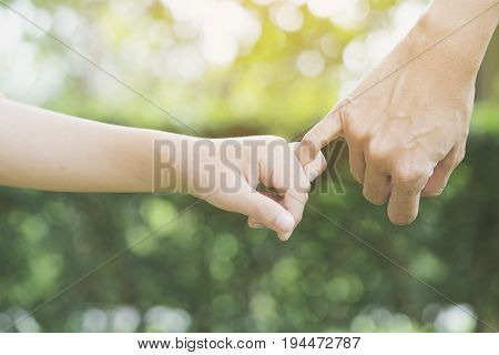A mother and her child hooking their fingers to make a promise