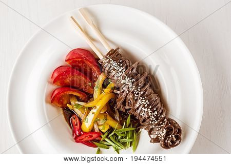Soba noodles of buckwheat Noodles of buckwheat yellow pepper, tomato and herbs. Pan-Asian cuisine. Place for text. Square photo size. Copy space. Top view