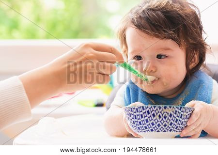 Happy little baby boy being fed by his mother