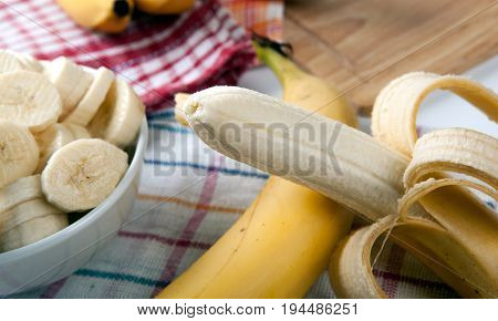 Slices of fresh bananas in a bowl and one banana close up