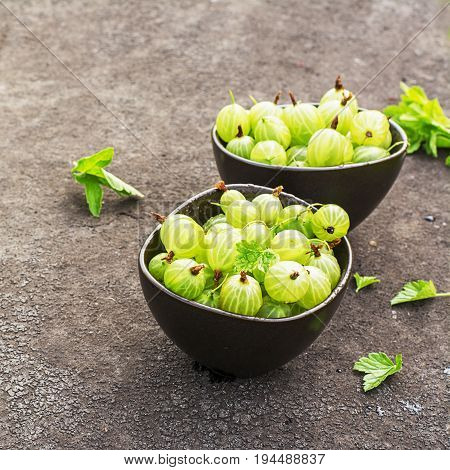 Fresh green gooseberries in a ceramic bowl on a dark background. Top view.