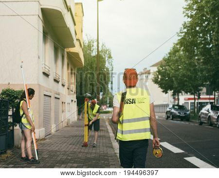 STRASBOURG FRANCE - MAY 30 2017: Students from the Institut National des Sciences Appliquees de Strasbourg performing a survey by theodolite for civil engineer checking surveyor equipment tachometer or theodolite outdoors at construction site in modern Fr
