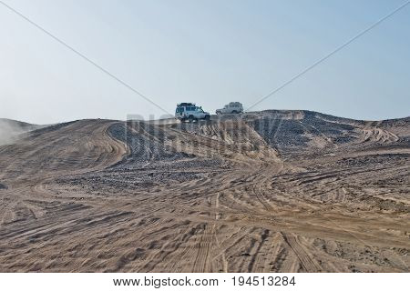 Wheel tracks on sand dunes and cars driving in desert on blue sky background. Safari trip on 4x4 jeeps. Offroad adventure. Extreme activity. Travel travelling. Summer vacation