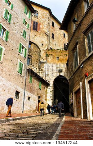 PERUGIA, ITALY. October 26, 2013: Uphill road with stairs in the historic center of Perugia in Italy. Some people walking on the street. Ancient buildings.