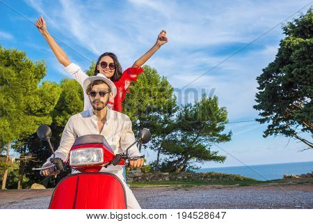 Happy free freedom couple driving scooter excited on summer holidays vacation. Young multiethnic couple.