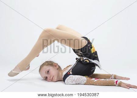 Sport concepts and Ideas. Young Caucasian Female Rhythmic Gymnast Athlete In Professional Competitive Suit Doing Backbend While Posing in Studio Against White. Horizontal Image