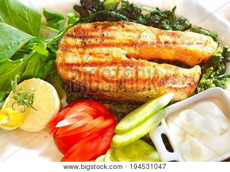 Grilled salmon closeup with fresh salad and lemon