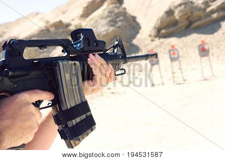 Man aiming machine gun at firing range, close up of hands