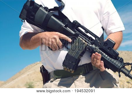 Man holding machine gun at firing range, mid section