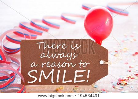 One Label With English Quote There Is Always A Reason To Smile. Party Decoration Like Streamer, Confetti And Balloon. Wooden Background With Vintage, Retro Or Rustic Syle