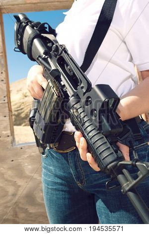 Woman holding machine gun at firing range, mid section