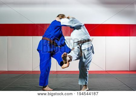 Two young women fight judo on tatami