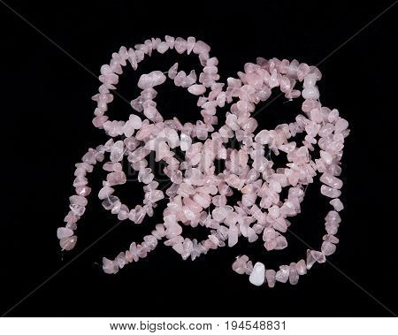 Polished rose quartz strings on black background