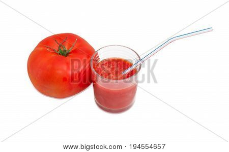 One fresh ripe tomato and tomato juice in glass with bendable drinking straw on a light background