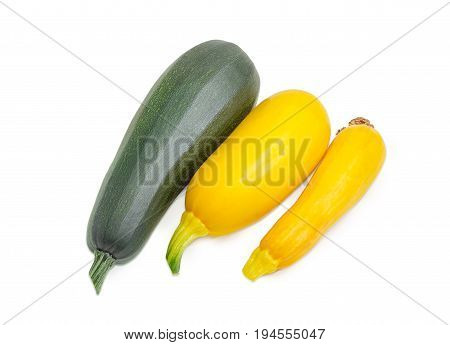 One fresh dark green zucchini and two yellow vegetable marrows on a light background