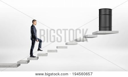 A businessman on white background walking up a concrete block stairs where a black oil barrel stands on the top. Oil and gas industry. Procurement business. Commodities trading.