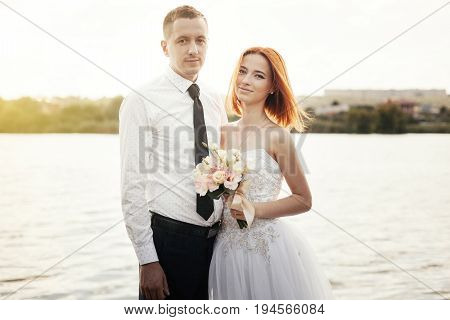 Elegant Gentle Stylish Groom And Bride Near River Or Lake. Wedding Couple In Love