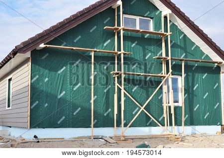 KYIV UKRAINE - JULY 11 2017:   Building Repair Remodeling House with Plastic Siding and Insulation Membrane Mineral Wool.Foundation insulation with styrofoam. Installing Rigid Foam Insulation.