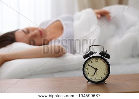 Sleepy young woman stretching hand to ringing alarm willing turn it off. Early wake up, not getting enough sleep, getting work concept