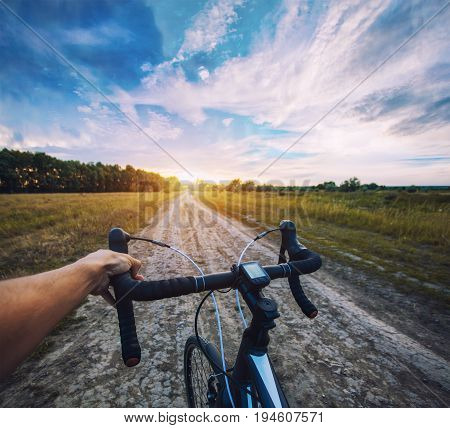cyclist rides on the meadov dirt road on a Cyclocross bike. first-person view