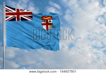 National flag of Fiji on a flagpole in front of blue sky.