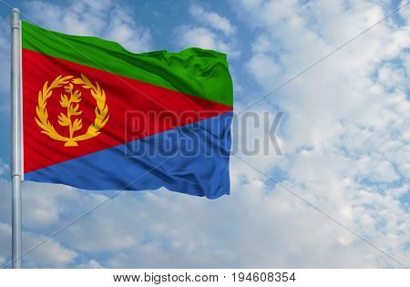 National flag of Eritrea on a flagpole in front of blue sky.