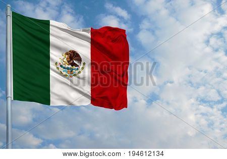 National flag of Mexico on a flagpole in front of blue sky.