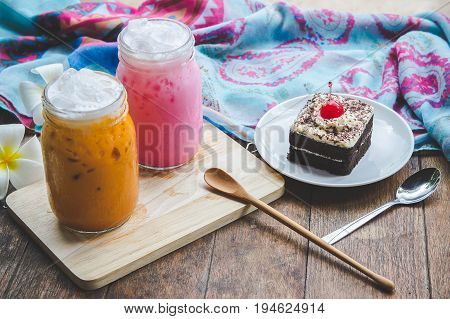 thai tea milkshake and pink milkshake beverage thailand style and cake chocolate dessert on wood table