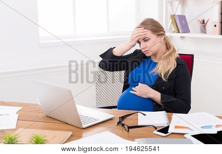 Tired pregnant businesswoman at office copy space. Expectant business lady feeling sick at work, gestosis concept