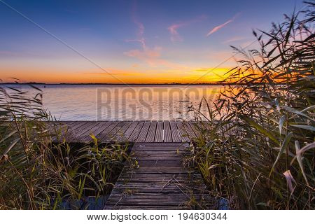 Sunset Over Wooden Boardwalk On The Shore Of A Lake