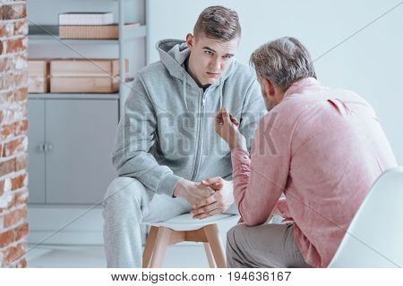 Rebellious teenager talking with counselor about his issues