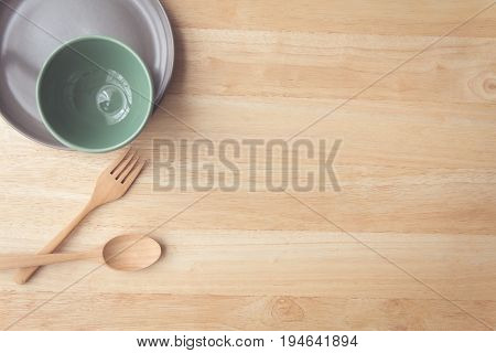 plate and cup with spoon and fork on wood table with copy space