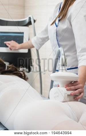 Woman in special white suit getting anti cellulite massage in a spa salon. LPG, and body contouring treatment in clinic. Lipomassage procedure on female body.