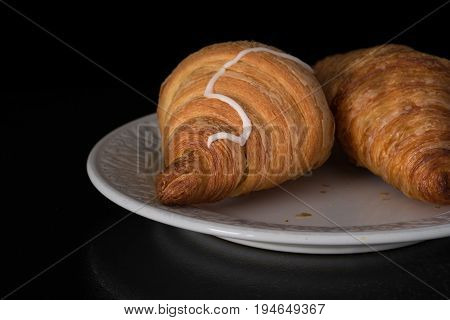 Cinnamon crescents croissant on white plate on the black background