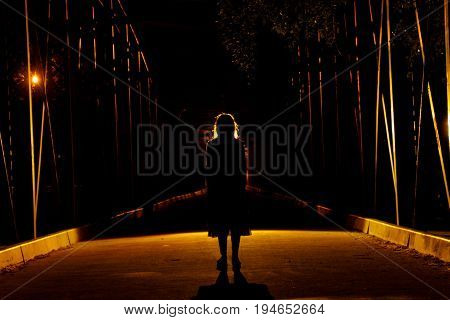 Girl in penumbra on an old and dimly lit bridge