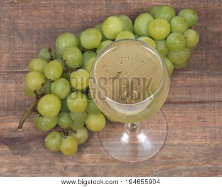 Glass of white wine and ripe organic green grapes isolated on vintage wooden background