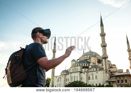 A traveler with virtual reality glasses. The concept of virtual travel around the world. In the background, the blue mosque Sultanahmet in Istanbul. Modern imaging technology.