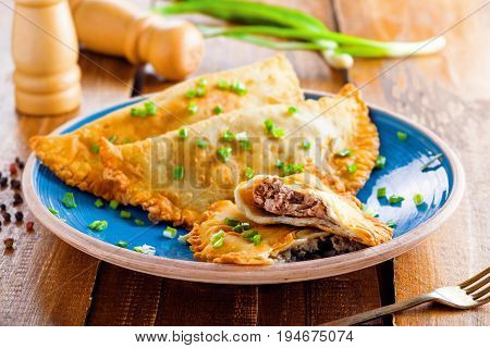 Native Russian Turkish Ukrainian Romanian and Tatar food on a table. Delicious cheburek with meat and spring onion. East cuisine meat pastry.
