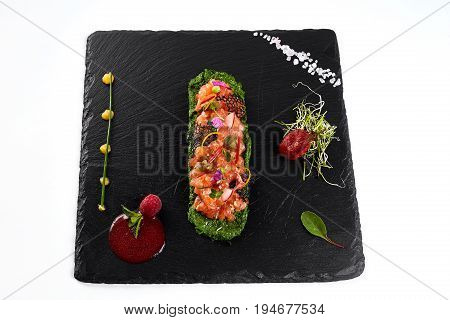 fresh salmon tartar with salt and herbs, studio shot. Fish tartar on black shale