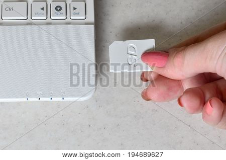 A Female Hand Inserts A White Compact Sd Card Into The Corresponding Input In The Side Of The White