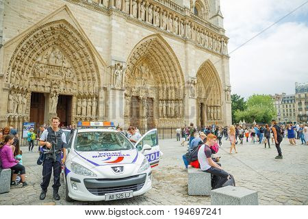 PARIS, FRANCE - JULY 2, 2017: Notre Dame de Paris central main facade, with police car and policemen, keeping security of this high sensitive tourist landmark, after recent terrorist threat in Paris.