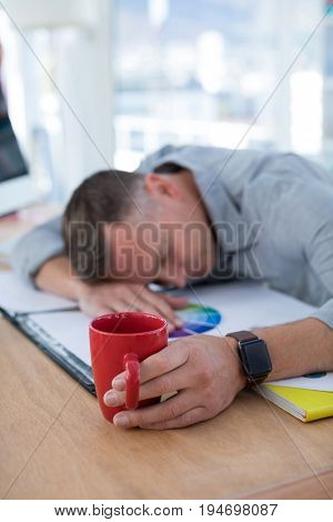 Tired male executive sleeping on desk in the office